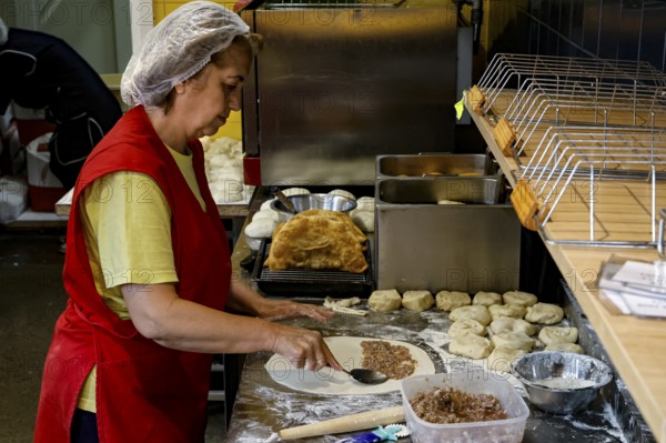 A woman prepares fresh chebureks at a stand at the Central Market in Riga, Riga, Latvia