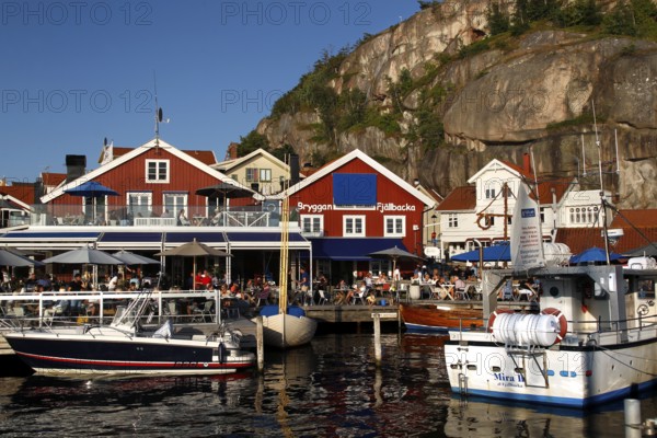 Colourful houses and boats at Fjällbacka harbour surrounded by natural cliffs, Fjällbacka, Sweden