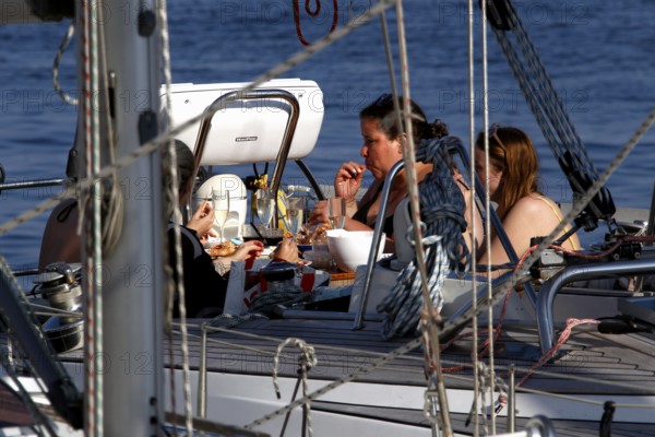 Group of people relaxing on a sailboat in harbour, Smögen, Västra Götaland, Sweden