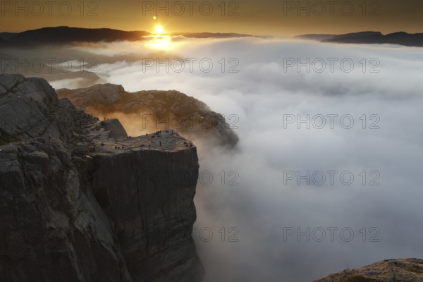 The rising sun paints dramatic colors over the sea of clouds at Preikestolen, Preikestolen, Rogaland, Norway