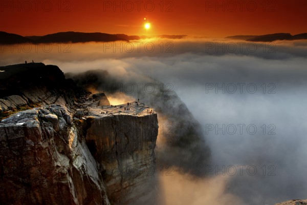 A golden horizon spreads over the sea of clouds and the mighty cliffs of Preikestolen, Preikestolen, Rogaland, Norway
