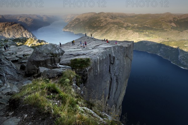 Preikestolen towers over the majestic fjord with hikers