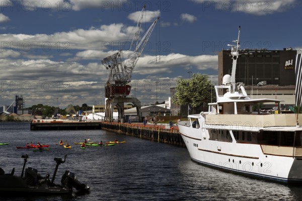 Old port of Tjuvholmen with ships and cranes against a cloudy backdrop, Oslo, Norway