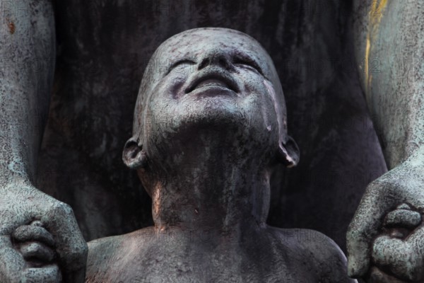 Detail of a bronze sculpture in Vigelandsparken shows a child's face with expressive facial expressions, Oslo, Norway