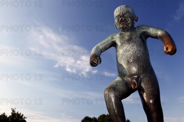 Bronze statue of an angry child against a blue sky in Vigelandsparken, Oslo, Norway