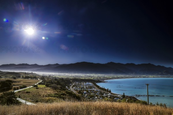 Extensive view of Kaikoura with mountains and sea under bright skies, zero