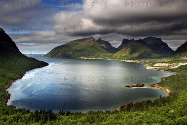 View of the picturesque coastline of Bergsbotn with majestic mountains and calm water, Senja, Norway