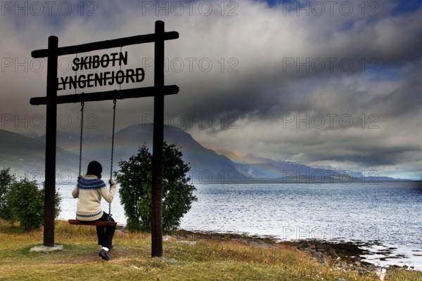 Child swings with a view of Lyngen Fjord under dramatic sky, Lyngen Fjord, Norway