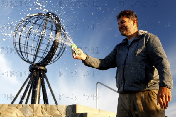 Man spraying globe sculpture at North Cape against clear sky, North Cape, Norway