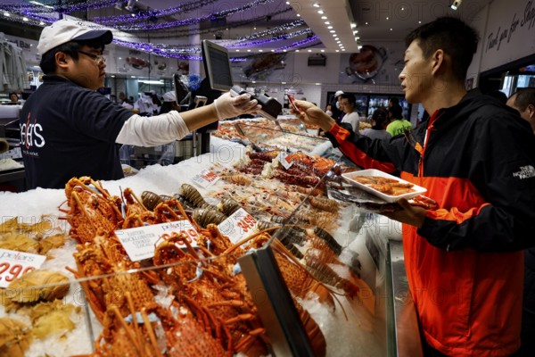 A salesman and a customer exchange friendly ideas at a lively fish stand, Sydney, Australia