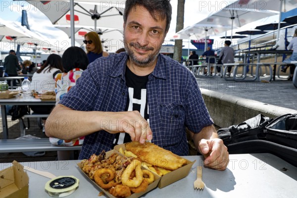 Man enjoying fish and squid rings outdoors at Sydney Fish Market, Sydney, New South Wales, Australia