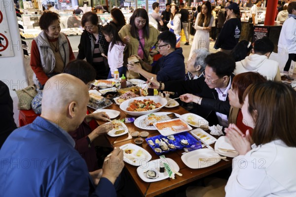 People eat at a table at the lively Sydney fish market, Sydney, New South Wales, Australia