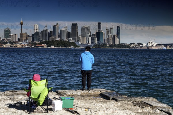 View of Sydney's skyline from Bradleys Head with people fishing in the foreground, Sydney, New South Wales, Australia