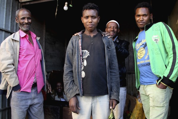 Group of men posing in front of a small shop and smiling at the camera, Awaday, Afar, Ethiopia