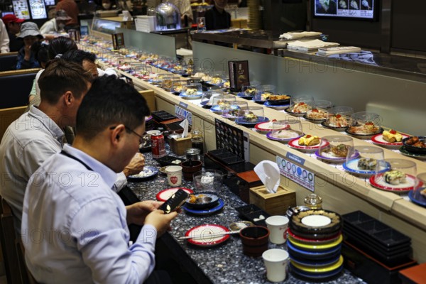 Sushi on an assembly line in the busy food court of a department store, Busan, South Korea
