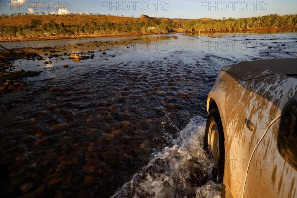 A vehicle crosses the Pentecost River through a shallow ford when the sun is low, Pentecost River, Australia