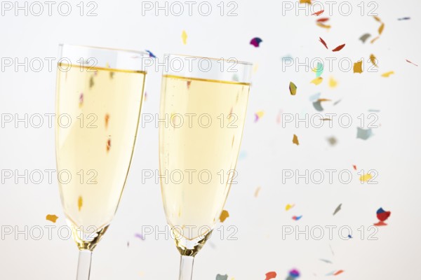 Two champagne glasses with colorful confetti in the background