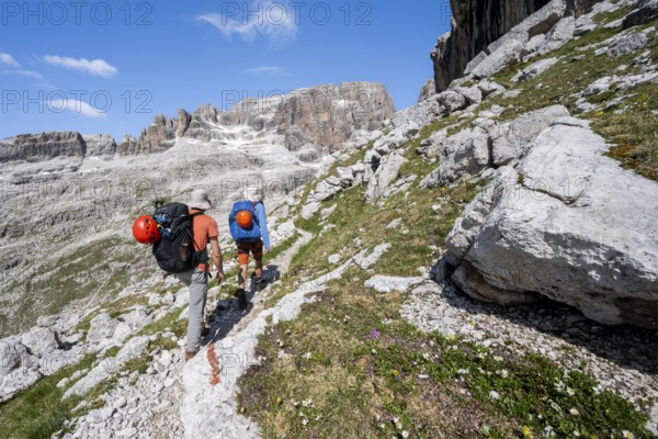 Two mountaineers on a hiking trail to Sella della Tosa, mountainous landscape in the Brenta Mountains, Brenta-Adamello Natural Park, Trentino, Italy