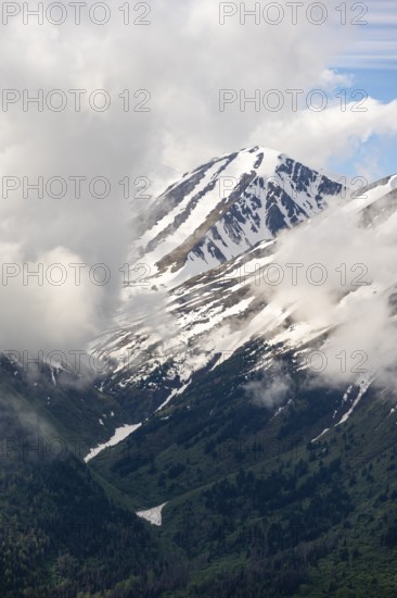 Fog sweeps around mountain peaks with remnants of snow, view from Slaughter Ridge Trail, Cooper Landing, Kenai Peninsula, Alaska, USA