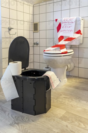 Symbolic picture blackout, extensive, prolonged power failure, in private environments, without electricity, the water supply also fails, toilet flush no longer works, emergency toilet, mobile toilet, camping toilet as an emergency replacement, disposal in bags