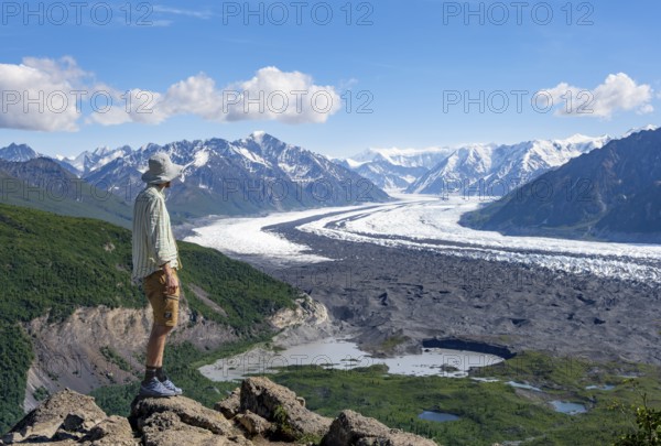 Young man enjoying the view, view of impressive mountain landscape with Matanuska glacier and glaciated mountain peaks, Lion's Head, Chugach Mountains, Alaska, USA