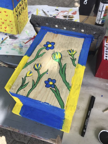 Lower Saxony, Germany, painted bird house in blue and yellow with flowers. Ukrainian students' creative craft project with spring-like design