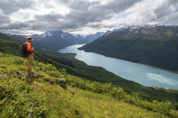 Mountaineer enjoys views of blue lake and mountains on Twin Peaks Trail, Eklutna Lake, Chugach Mountains, Chugach State Park, Alaska, USA