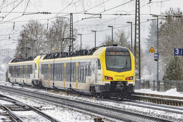 Regional train from Arverio on its way through a winter landscape in snowfall. The railcar train is painted by the Baden-Württemberg mobility brand bwegt. A train on the line in the Deutsche Bahn AG rail network. Amstetten, Baden-Württemberg, Germany
