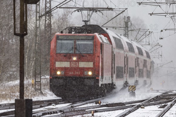 RegionalExpress RE on the road through a winter landscape in snowfall. A train on the line in the Deutsche Bahn AG rail network. Amstetten, Baden-Württemberg, Germany
