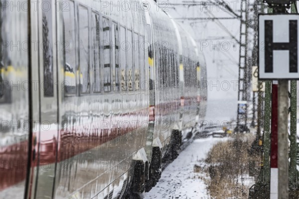 ICE traveling through a winter landscape in snowfall. A train on the line in the Deutsche Bahn Amstetten rail network, Baden-Württemberg, Germany
