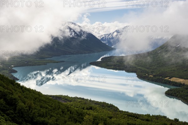 View of snowy mountains in spring and turquoise Kenai Lake with reflection, Slaughter Ridge Trail, Cooper Landing, Kenai Peninsula, Alaska, USA