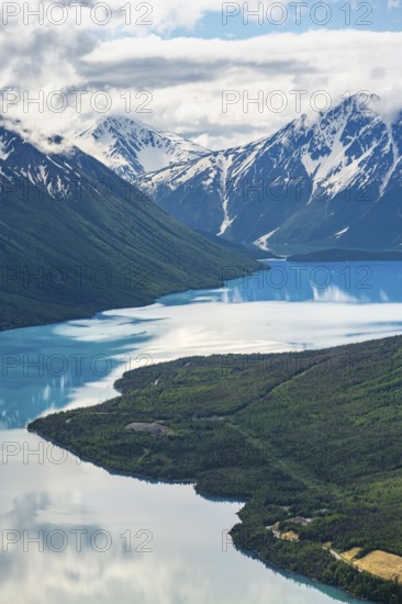 View of snowy mountains in spring and turquoise Kenai Lake with reflection, Slaughter Ridge Trail, Cooper Landing, Kenai Peninsula, Alaska, USA