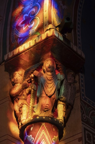 Issoire. Pillar (The Annunciation made to Mary) . The figures are illuminated by colorful light shining through a stained glass window inside Saint Austremoine Abbey, Puy de Dome, Auvergne Rhone Alpes, France