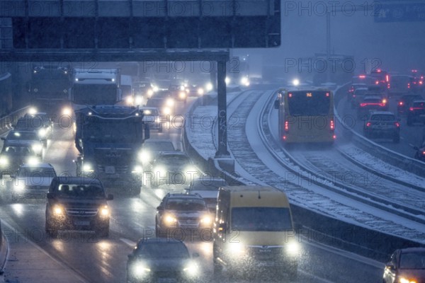 Winter weather, motorway traffic, A40 motorway, Ruhrschnellweg, in Essen, at the Essen-East motorway junction, snowfall, traffic jams, heavy flowing traffic, bus lane between roads, public transport, North Rhine-Westphalia, Germany