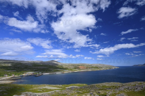 Green meadows on the banks of Syltefjord with clouds in the blue sky, landscape with a lake and green meadows under a cloudy sky, Nordfjord, Båtsfjord, Finnmark, Norway