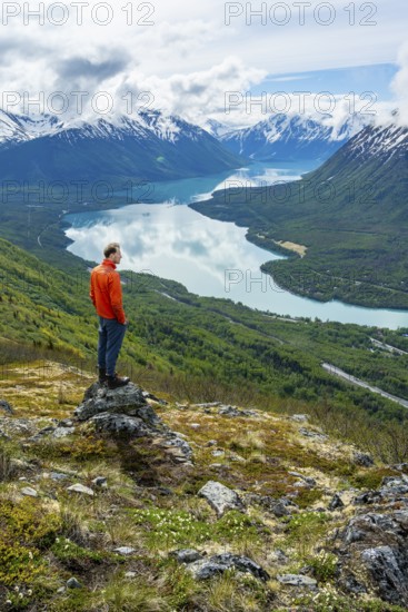 Climber enjoying the view, Slaughter Ridge Trail, view of snowy mountains and turquoise blue Kenai Lake, Cooper Landing, Kenai Peninsula, Alaska, USA