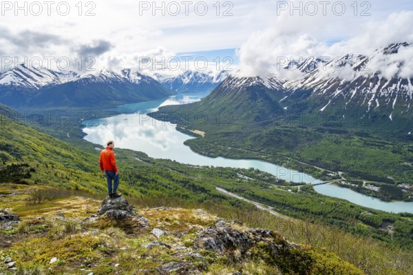 Climber enjoying the view, Slaughter Ridge Trail, view of snowy mountains and turquoise blue Kenai Lake, Cooper Landing, Kenai Peninsula, Alaska, USA