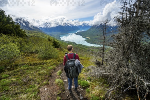 Climbers on a hiking trail, Slaughter Ridge Trail, view of snowy mountains and turquoise lake Kenai Lake, Cooper Landing, Kenai Peninsula, Alaska, USA