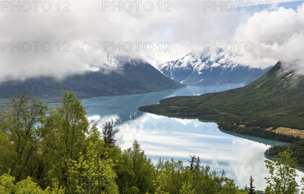 View of snowy mountains in spring and turquoise Kenai Lake with reflection, Slaughter Ridge Trail, Cooper Landing, Kenai Peninsula, Alaska, USA