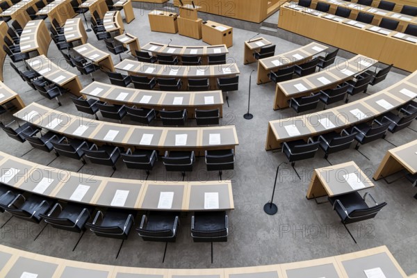 Plenary hall deserted with the seats of deputies and the government bank. Behind it is the coat of arms of the federal state. The state parliament of Baden-Württemberg is the state parliament based in Stuttgart, Baden-Württemberg, Germany