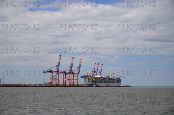 The container ship OOCL Germany with 59 m width and 400 m length of one of the largest container ships in the world maneuvers between cranes in Jade Weser Port, Wilhelmshafen, Jade Bay, Lower Saxony, Germany