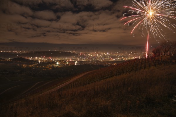 View from Kapellberg near Fellbach across the Neckar Valley to Stuttgart on New Year's Eve from 2025 to 2026. The television tower on the horizon as firecrackers and rockets light up the night sky at the turn of the year and greet the new year