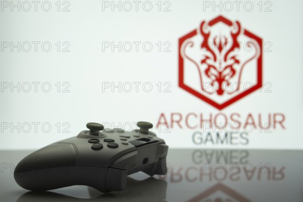 Dhaka, Bangladesh- 20 Mar 2025: A close-up of a white gamepad with the ARCHOSAUR GAMES seen on screen in the background