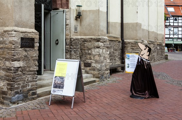 Bruno, the HB-Männchen or HB Man, a cartoon character from German commercial television advertised the HB cigarettes, information sign in front of market church St. Aegidien or Saint Giles, Osterode, Upper Harz region, Lower Saxony, Germany
