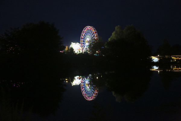 Fairground in Ulm Friedrichsau at night, folk festival, hustle and bustle, fair, Ferris wheel, amusement park, amusement attraction, ride, artificial light, darkness, reflection in natural lake, Ausee, Ferris wheel, Ulm, Baden-Württemberg, Germany
