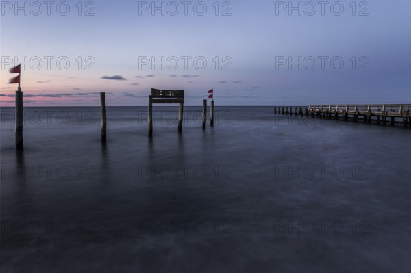 Wooden sign in the sea with inscription Zingst and wooden walkway, long exposure, evening light, Zingst, Fischland-Darß-Zingst, Western Pomerania National Park, Mecklenburg-Western Pomerania, Germany