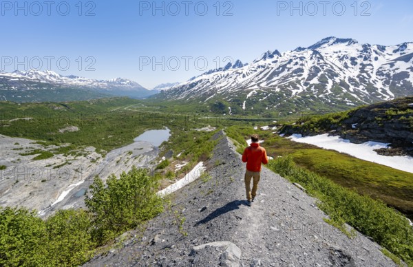 Hikers on glacial moraine, view of the vast Tsina River valley with mountains, Worthington Glacier Lagoon, Worthington Glacier State Recreational Site, Chugach Mountains, Alaska, USA