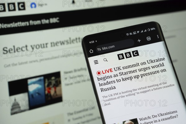Dhaka, Bangladesh - 17 March 2025: BBC Newspaper website is displayed on a smartphone screen, and the website is visible on a computer screen in the background
