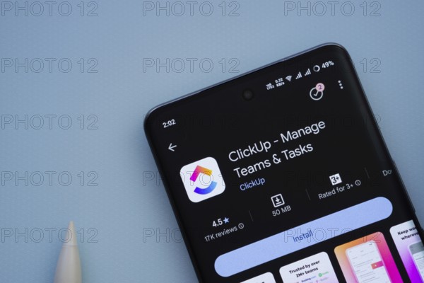 Dhaka, Bangladesh- 29 May 2025: On a blue surface, a smartphone displays the ClickUp app within the Google Play Store