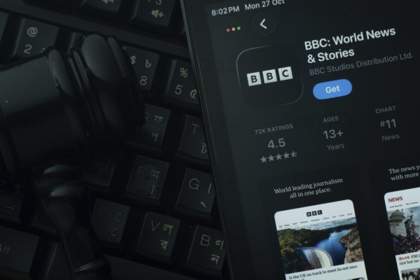 Dhaka, Bangladesh- 28 Oct 2025: An iPad displaying the BBC app against a judge's gavel and dark keyboard background